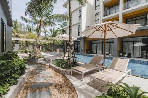 una piscina del resort con due sedie e un ombrellone di 1412 Wyndham Gardens Elegant Pool Condo a Nai Thon Beach