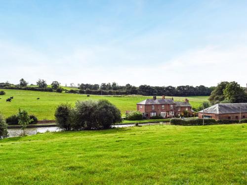 a field of green grass with a house and a river at Grace in Braunston
