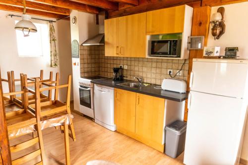 une cuisine avec des armoires en bois et un réfrigérateur blanc dans l'établissement Gite Hiver au coeur de la fôret max 5 personnes, à Le Soulié