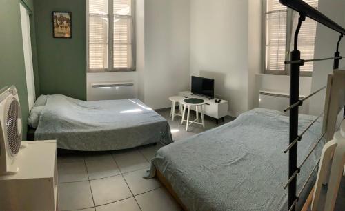 a room with two beds and a desk with a computer at STUDIO Dole Grevy deux étoiles, in Dole