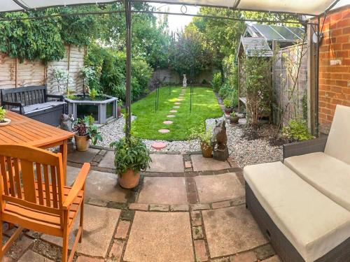 a backyard with a garden with a couch and a table at Burwood Cottage in Rotherfield Peppard