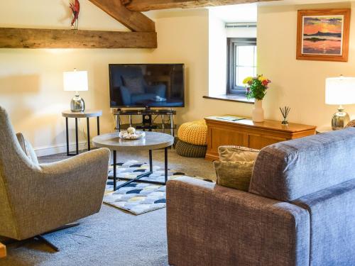 un salon avec un canapé et une télévision dans l'établissement The Studio At Malt Kiln Cottage, à Grizebeck
