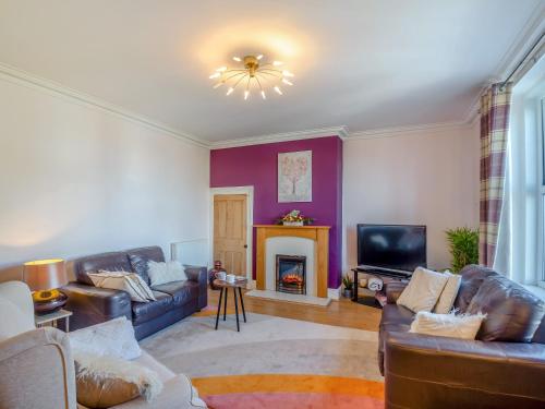 a living room with couches and a tv and a fireplace at Rhiw Bank Apartment in Colwyn Bay
