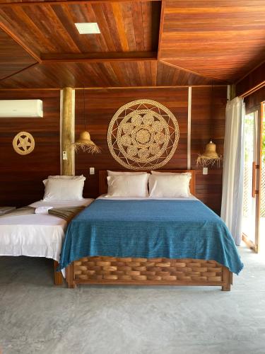 a bedroom with two beds with wooden walls at Villa Caravelas Praia de Moitas in Amontada