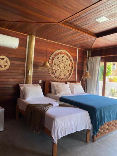 two beds in a room with wooden walls at Villa Caravelas Praia de Moitas in Amontada