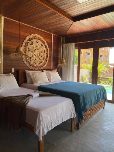 a bedroom with two beds and a large window at Villa Caravelas Praia de Moitas in Amontada