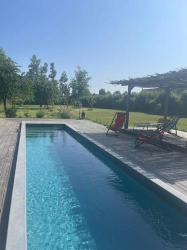 une piscine avec deux chaises et un parasol dans l'établissement La maison Rouge, à Bard-lès-Époisses