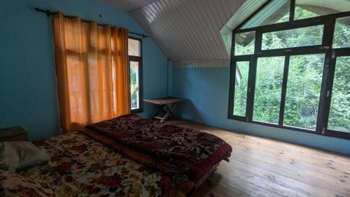 a bedroom with a bed in a room with windows at Alpine Homes in Kulu