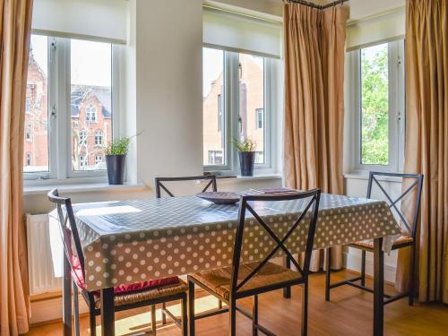 a dining room with a table and chairs and windows at Lime Court - Cottages in Leatherhead