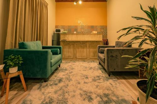 a living room with two green couches and a piano at Na Hotel in San Cristóbal de Las Casas