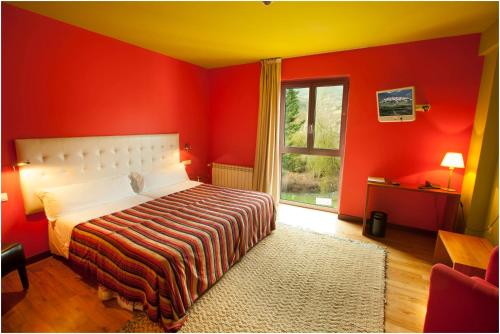 a red bedroom with a bed and a window at Hotel Ibaiondo in Olave