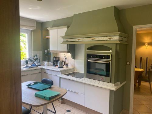Il comprend une cuisine équipée d'une cuisinière. four supérieur à côté d'une table dans l'établissement Villa des Pins Hardelot, à Neufchâtel-Hardelot