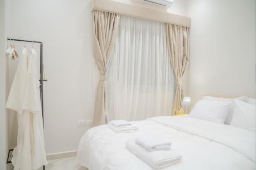 a white bed with two white towels on it at Ground Floor Gem - Patio Lounge in Cairo