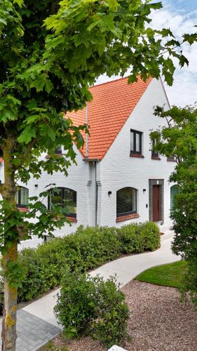 a white house with an orange roof at House W - North Sea Stays in De Haan