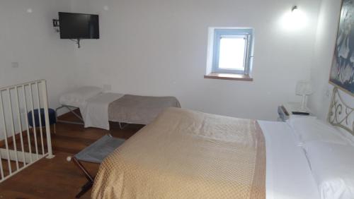 a room with two beds and a window and a tv at Borgo Rosso di Sera - Resort Country Chic in San Lucido