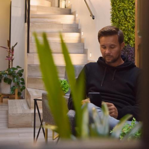 a man sitting on a chair looking at his cell phone at Na Hotel in San Cristóbal de Las Casas