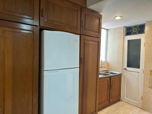 a kitchen with a white refrigerator and wooden cabinets at Apartamento con hermosa vista y soleado en Sopocachi in La Paz