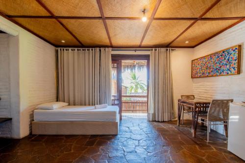 a bedroom with two beds and a table and a window at Dayo Hotel in Flecheiras