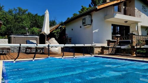 a swimming pool with an umbrella and a house at СПА къща за гости Каза Роза - Swiss Style Chalet Casa Rosa SPA Guest House in Kyustendil