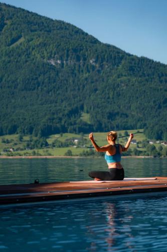 a woman sitting on a boat in the water at Romantik Residenz (Ferienwohnungen Hotel Im Weissen Rössl) - Dependance in St. Wolfgang