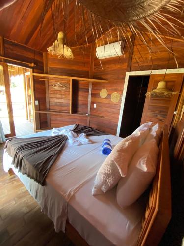 a large bed in a room with wooden walls at Villa Caravelas Praia de Moitas in Amontada
