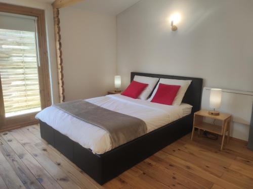 une chambre avec un grand lit avec deux oreillers rouges dans l'établissement chalet de Campagne avec option SPA - petit déj, à Wicquinghem