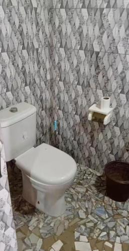 a bathroom with a white toilet and a shower curtain at Jamebougoum in Mar Lodj