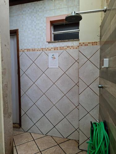 a bathroom with a tiled wall and a window at Apê confortável, com Alexa. Ótima localização in Ilhéus