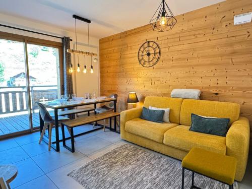 un salon avec un canapé jaune et une table dans l'établissement Magnifique Appartement 4* Les Gets, 48m², Proche Centre, Balcons, 6 Couchages, Services Inclus - FR-1-623-20, aux Gets