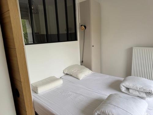 un lit avec des draps blancs et des oreillers dans une chambre dans l'établissement Appartement F3 avec balcons, domaine de l'hermitage, à Le Touquet-Paris-Plage