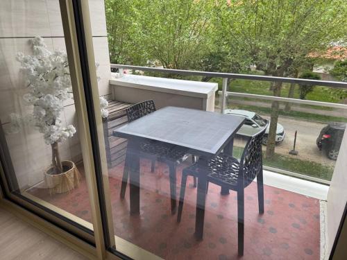une table noire et des chaises sur un balcon dans l'établissement Appartement F3 avec balcons, domaine de l'hermitage, à Le Touquet-Paris-Plage