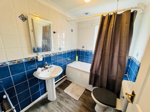 a blue tiled bathroom with a sink and a tub at Town centre with parking in Huntingdon