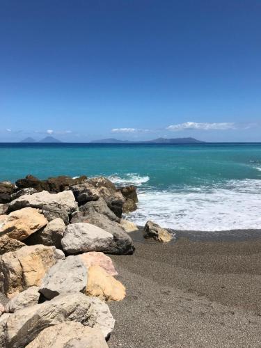 a group of rocks on a beach next to the ocean at Casa Rosy Sicilia in Brolo