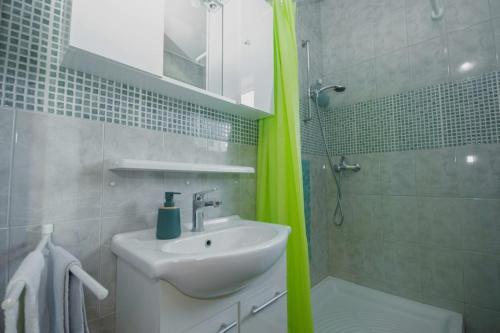 a bathroom with a sink and a green shower curtain at Apartment Kamenar 3 in Klimno