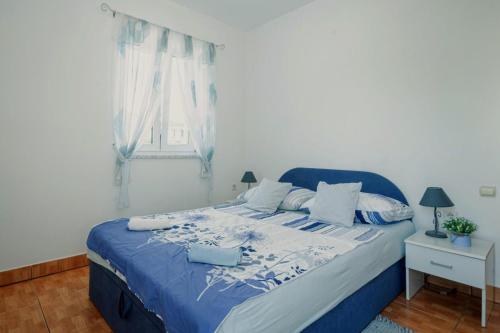 a bedroom with a bed with blue and white sheets and a window at Apartment Kamenar 3 in Klimno