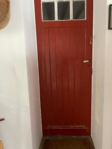 une porte rouge avec une fenêtre dans le couloir dans l'établissement Appartement en rez de jardin, à Ciboure
