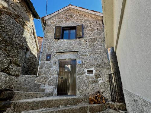 a stone building with a door and a window at Raízes da Serra - Casa Alvoco in Alvoco da Serra