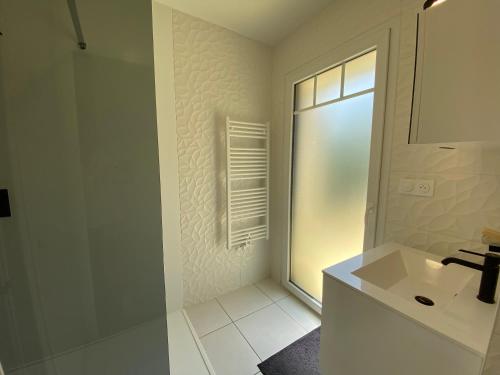 une salle de bain blanche avec un lavabo et une fenêtre dans l'établissement Maison vacance eco quartier, à La Teste-de-Buch