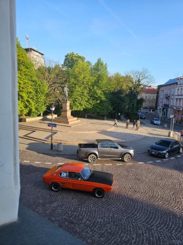 an orange car parked in a parking lot with other cars at Old Town View in Rzeszów