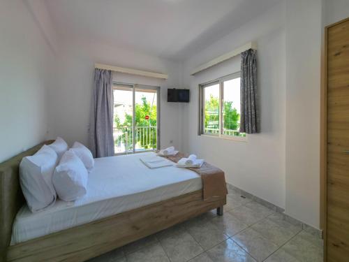 a bedroom with a bed with white walls and windows at ARETI Suites by SDR in Olympiaki Akti