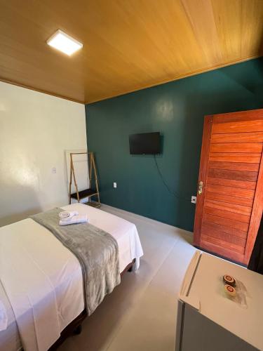 a bedroom with a bed and a flat screen tv at Vale dos Cristais Suítes in Alto Paraíso de Goiás
