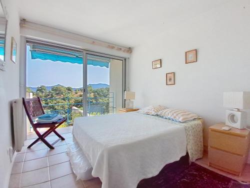 une chambre avec un lit et une grande fenêtre dans l'établissement Duplex avec terrasse & vue dégagée dans domaine privé à Mandelieu, à Mandelieu-la-Napoule