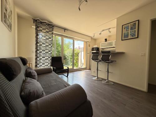 - un salon avec un canapé et un four micro-ondes dans l'établissement Charmant T2 à 2 min de la mer, avec Jardin Privé et clôturé, Parking, à proximité du Centre-Ville, à Cabourg