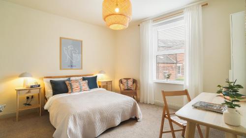 a bedroom with a bed and a table and a window at Crookes Gem with Garden & Alpacas Nearby in Walkley