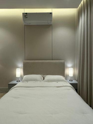a bedroom with a white bed with two lamps at استديو فندقي مع بلكونه في موقع استراتيجي in Dammam