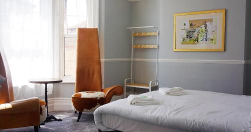 a bedroom with a bed and a chair and a window at The Loriston in Eastbourne
