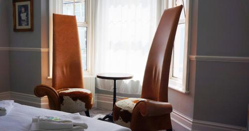 two chairs in a room with a bed and a window at The Loriston in Eastbourne