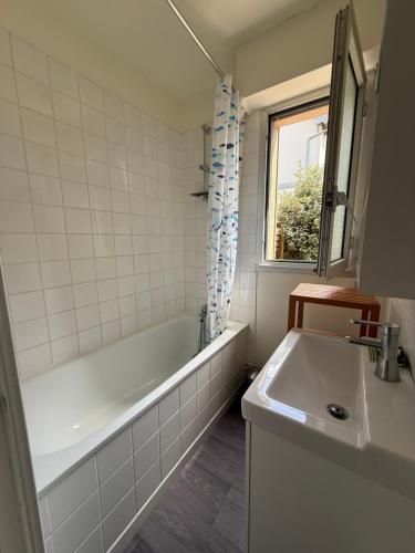 une salle de bain avec une baignoire et un lavabo dans l'établissement Charmant T2 à 2 min de la mer, avec Jardin Privé et clôturé, Parking, à proximité du Centre-Ville, à Cabourg