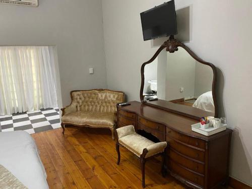 a bedroom with a dresser with a mirror and a chair at Boutique at milner guesthouse in Bloemfontein
