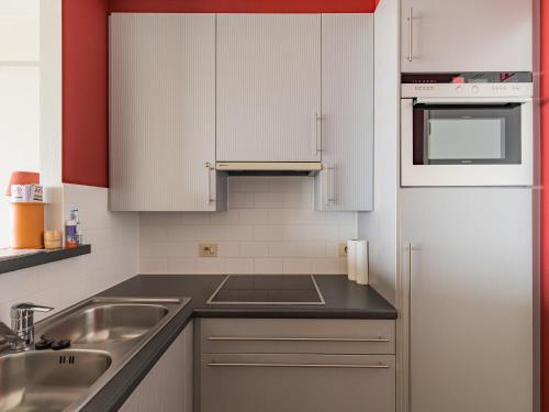 a kitchen with white cabinets and a sink and a refrigerator at Luxury 2-bedroom apartment with stunning sea view T207 in Blankenberge